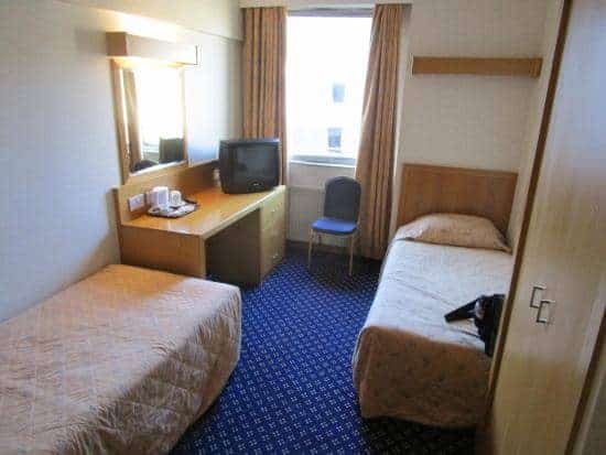 A standard room at the Royal National Hotel in London with two singles beds and a desk with tv