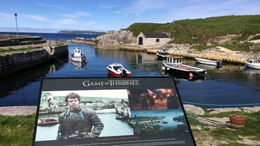 Ballintoy Harbour, Northern Ireland - a small picturesque fishing harbour located on the rugged coastline of County Antrim, with a collection of white-washed cottages, boats in the harbour, and rolling green hills in the background.