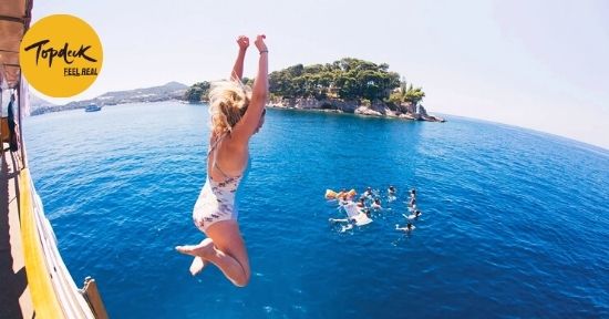 Woman jumping into Adriatic Sea from Topdeck Sail Croatia boat with a group of friends swimming close by