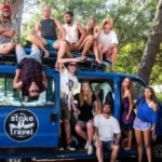 A group of young travellers on a Stoke Travel tour sitting in a blue camper van