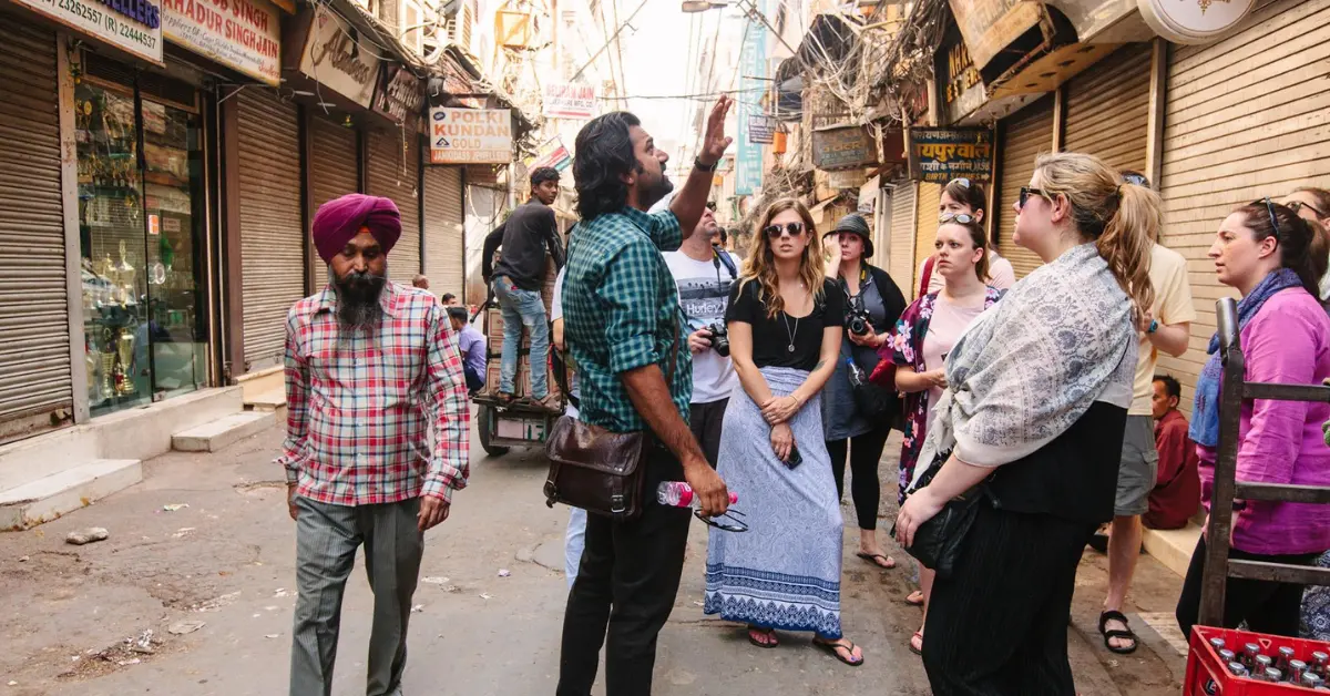 A group of young adults on an Intrepid Travel tour listening to a guide in an Indian market street