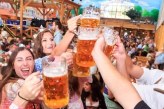 A group of young travellers clinking their steins together inside a beer tent at the Oktoberfest beer festival