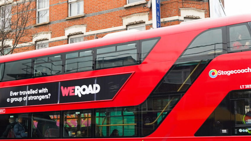 A famous red London bus adorned with the WeRoad advertising campaign