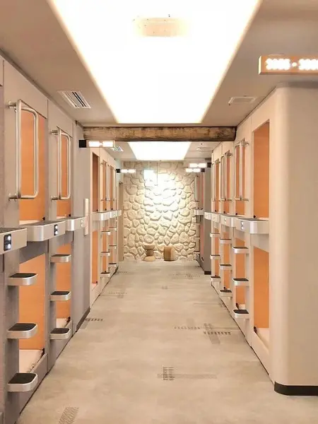 Interior view of Capsule Inn Osaka, featuring a corridor lined with rows of capsule units on both sides.