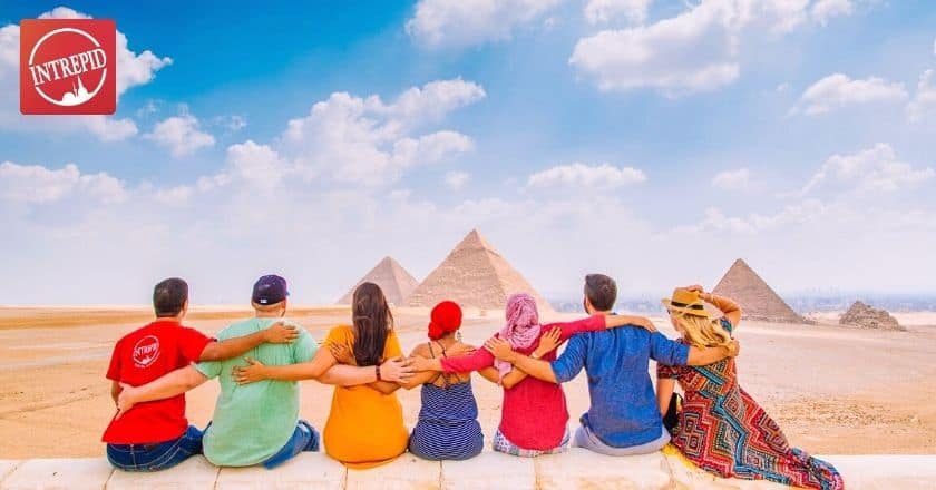 An Intrepid Travel group hugging in front of the Great Pyramids in Egypt